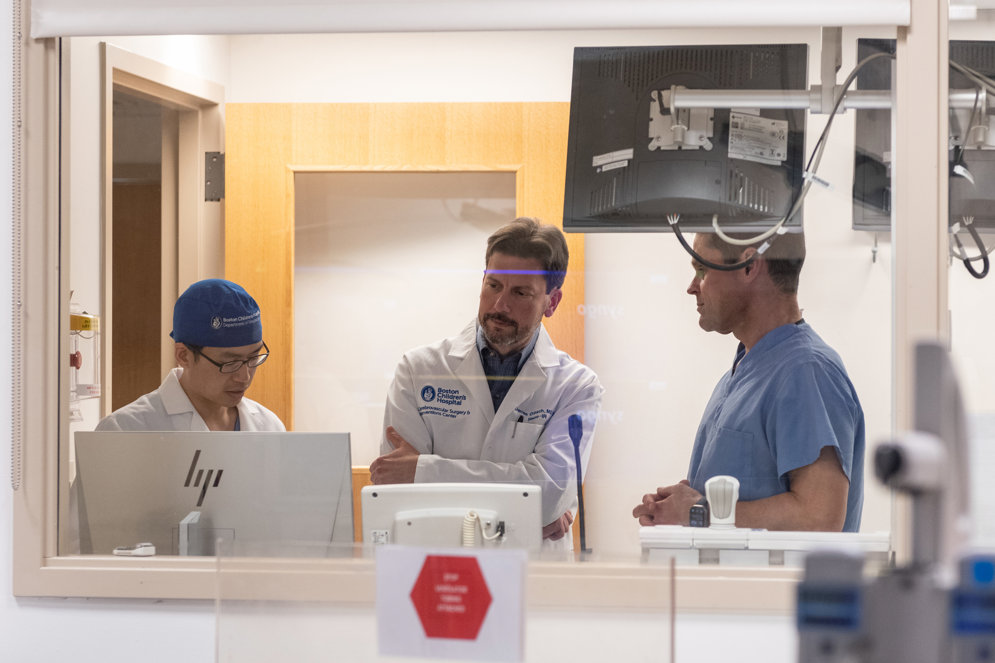 Doctors and surgeons gather in front of monitors to review information.