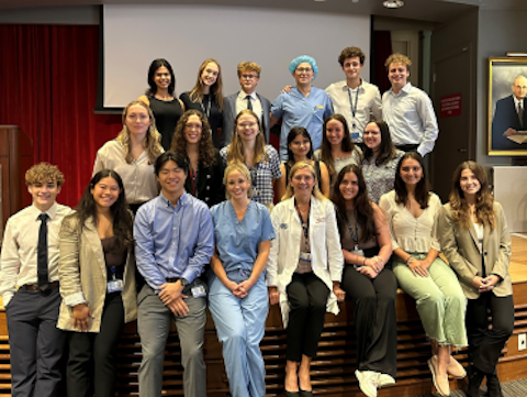 twenty men and women in three rows on an auditorium stage