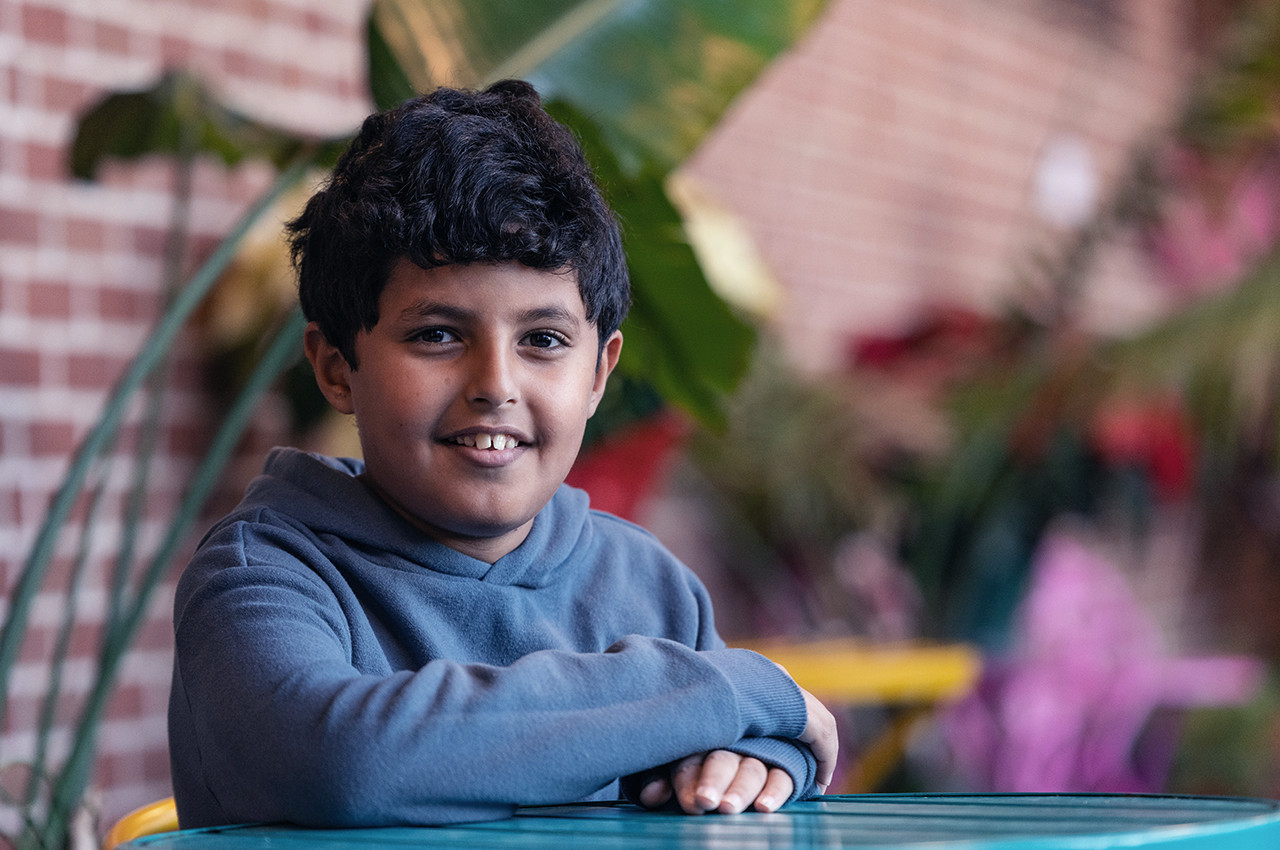 a boy sitting at a table and smiling