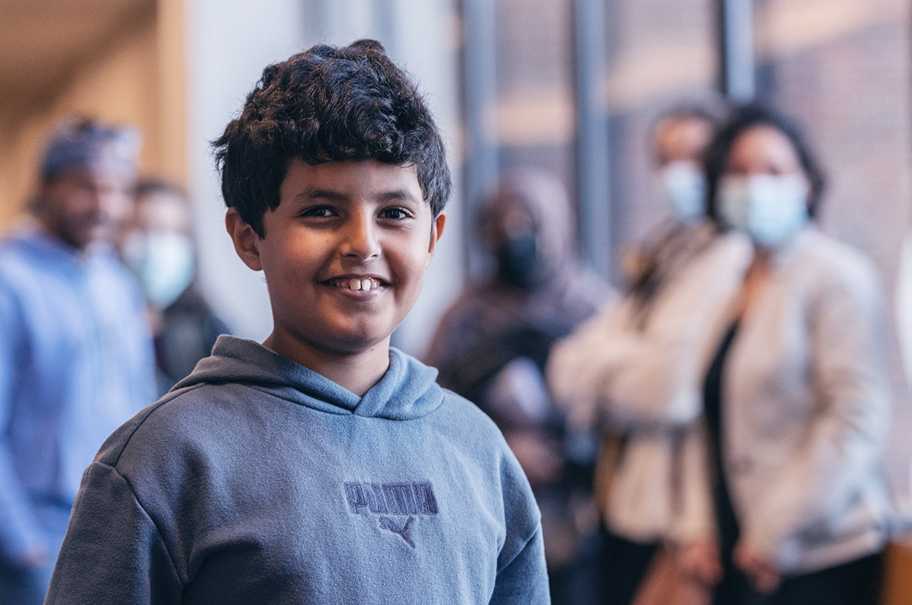 a boy smiling with his family behind him