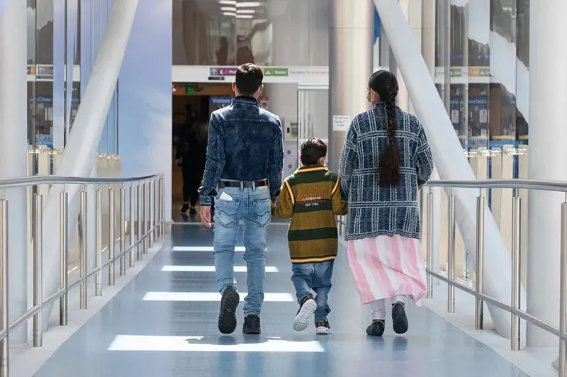 a mother father and child walking along a pedestrian bridge