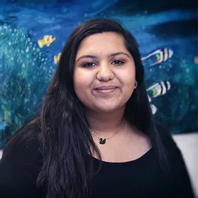 Smiling young teen girl stands in front of wall mural