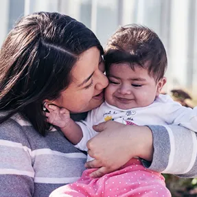 Smiling woman holds young baby.