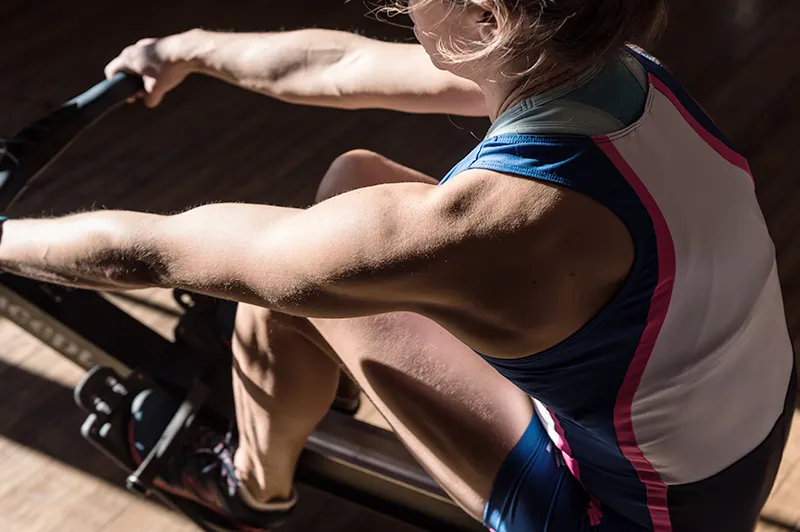 Rower grabs at straps on rowing machine during workout
