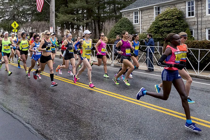 Large group of runners sprint down paved road