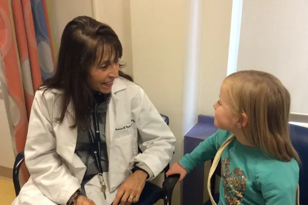 Clinician sitting in chair speaks to girl who's sitting down
