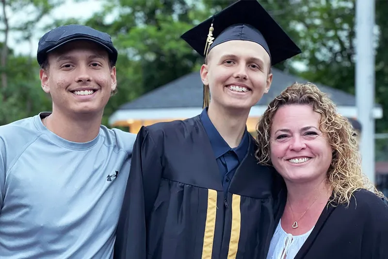Teen boy wearing hat, teen boy wearing high school graduation cap and gown, and mother