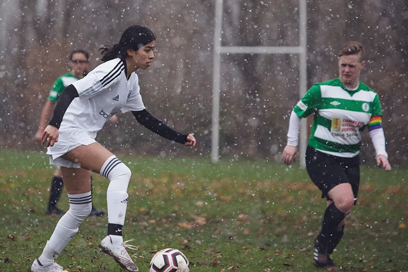 One female soccer player, at left, dribbles ball as opposing player approaches her