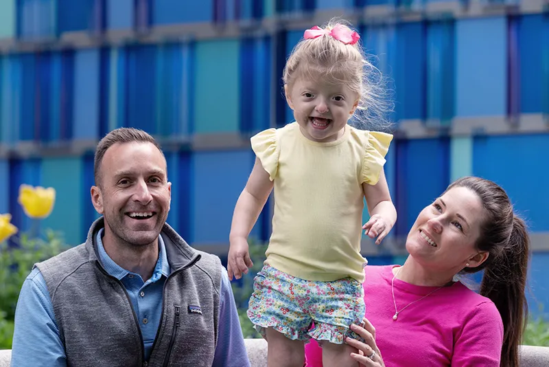 Young girl standing up, surrounded by her parents