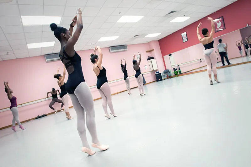 Ballet dancers practice pose with hands above their heads