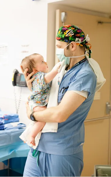 male doctor in blue scrubs holding toddler