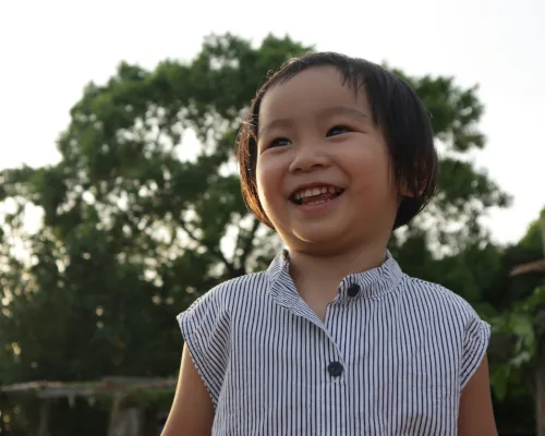 Young child smiles while looking off to their right