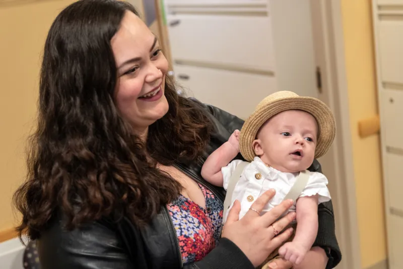 Woman swaddles hat-clad baby in her arms