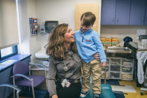 Adult woman holds younger boy in her arms