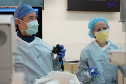 Two clinicians in scrubs speak in operating room